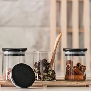 Set aus drei runden Gewürzgläsern aus Glas mit schwarzen Holzdeckeln auf Holzregal.