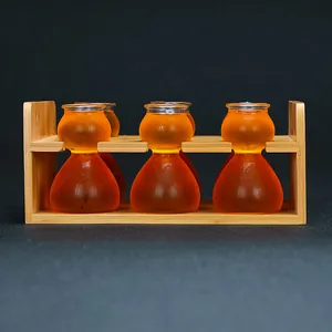 Vista detallada de seis vasos de chupito de cristal ámbar con forma de calabaza en soporte