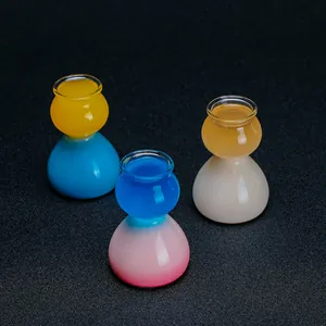 Detalle de tres vasos de chupito de vidrio con forma de calabaza y líquidos de colores.