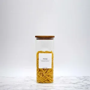 Transfarentes Vorratsglas aus Glas mit Akazienholzdeckel und Detail zum Penne-Nudel-Etikett