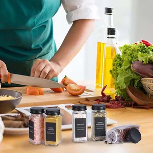 Lifestyle detail van vierkante glazen kruidenpotjes met zwarte deksels in keuken