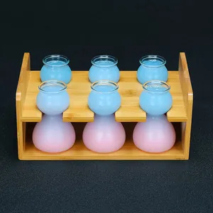 Detalle de seis vasos de chupito de cristal esmerilado en un soporte de madera de bambú