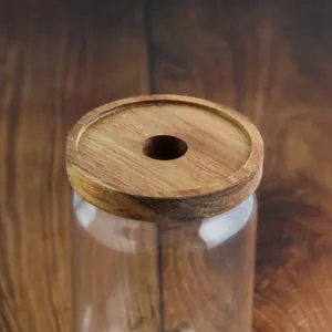 Gros plan du couvercle en bois d'acacia avec trou central sur un bocal en verre clair.