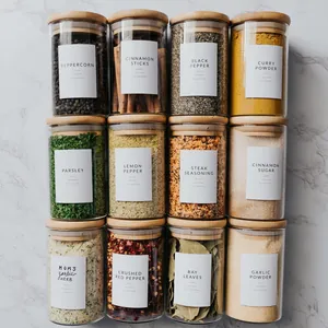 Détail de 12 pots à épices en verre avec couvercles en bambou et étiquettes minimalistes.