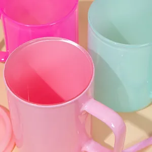 Primer plano de tazas de vidrio translúcido en rosa vibrante y verde menta con asas