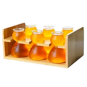 Vista detallada de seis vasos de chupito con forma de calabaza en un estante de bambú para bar.