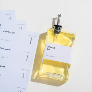 Detail van vierkante glazen oliefles met roestvrijstalen tuit en pindaolie etiket