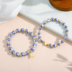 Detail view of blue and white porcelain bead bracelets with gold heart and letter A charms
