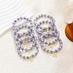 Detail of blue and white porcelain bead bracelets with gold initial charms in vintage style