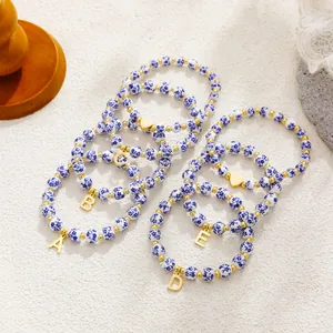 Detailed view of blue and white porcelain beaded bracelets with gold letter charms