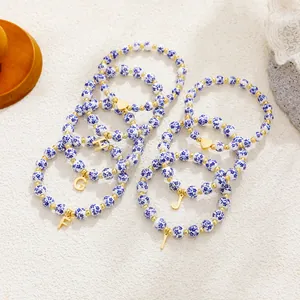 Detailed view of blue and white porcelain beaded bracelets with gold initial charms.