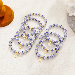 Detail view of blue and white floral porcelain bead bracelets with gold initial charms