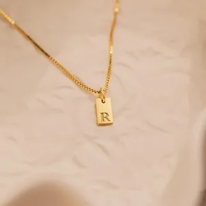 Close-up of 18K gold plated stainless steel square pendant with engraved letter R