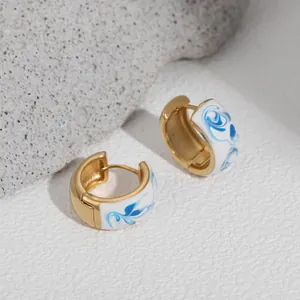 Detailed view of blue and white enamel porcelain style 18K gold plated hoop earrings.