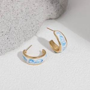Close-up of elegant blue and white enamel drip hoop earrings with 18K gold plated finish