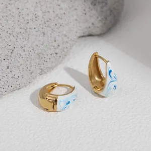Detailed view of blue and white enamel hoop earrings with 18K gold plating finish