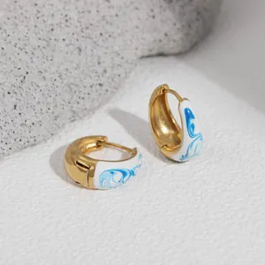 Macro detail view of 18K gold plated hoop earrings with blue swirl enamel inlay