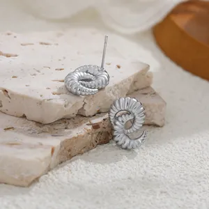 Vista detallada de pendientes de plata con textura irregular sobre losas de piedra natural