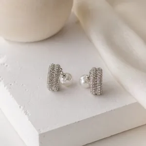 Vista detallada de pendientes de clip plateados de doble capa con elegante perla colgante