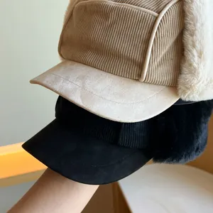 Close-up of beige and black corduroy trapper hats with thick plush ear flaps.