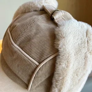 Close-up detail of a khaki corduroy trapper hat with thick beige plush lining for warmth.