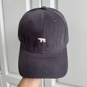 Gros plan d'une casquette de baseball gris anthracite avec broderie d'ours polaire