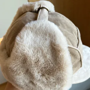Detailed close-up view of a beige corduroy winter trapper hat with soft faux fur