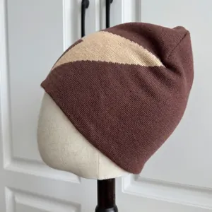 Detalle del tejido de un gorro de punto marrón y beige sobre una cabeza de maniquí.