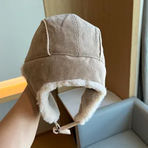 Detail view of khaki corduroy trapper hat with soft white plush lining and ear flaps.