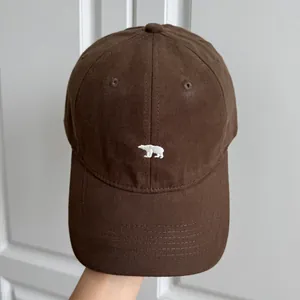 Gros plan d'une casquette de baseball marron avec motif ours polaire brodé blanc.