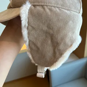 Close-up of beige corduroy trapper hat with soft faux fur lining and earflap detail