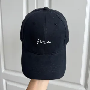 Gros plan d'une casquette de baseball noire minimaliste avec broderie 'me' blanche