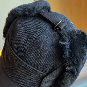 Macro detail view of black corduroy fabric and faux fur lining on a warm winter earflap hat.