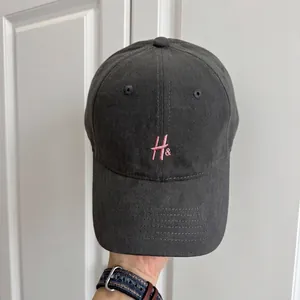 Primer plano de gorra de béisbol retro gris con detalle de bordado rosa H&