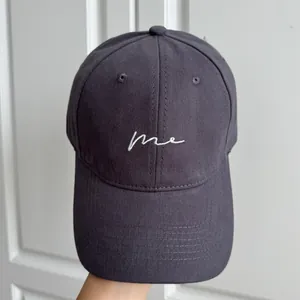 Gros plan d'une casquette de baseball gris foncé avec broderie 'me' blanche