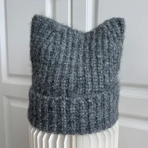 Macro detail of a dark grey knitted cat ear beanie showing soft mohair fluffy texture
