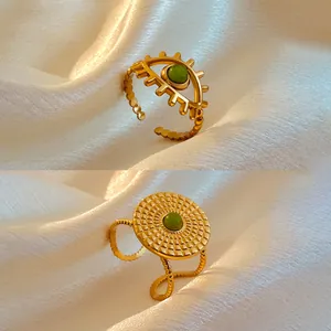 Macro view of gold plated stainless steel retro rings with green stones on white silk