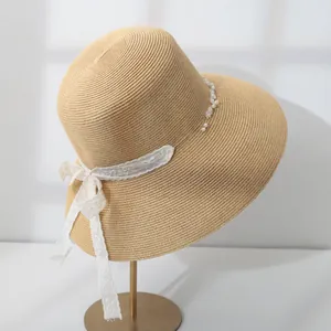 Detailed side view of women's straw sun hat with white lace bow and pearl accents