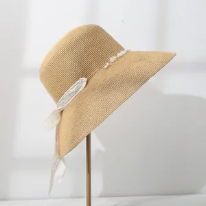 Close-up side view of a stylish straw bucket hat featuring pearl and lace ribbon detail