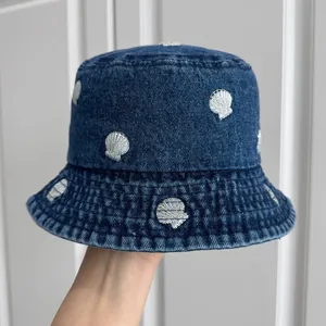 Close-up of blue denim bucket hat with silver embroidered shell patterns for summer