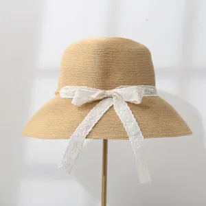 Close-up detail of women's summer straw sun hat featuring an elegant white lace bow