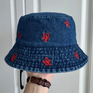 Detailed macro view of a blue denim bucket hat featuring red lobster embroidery