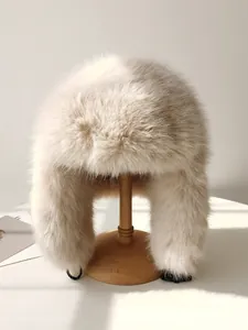 Primer plano de un gorro ruso de piel sintética beige sobre un soporte de madera.
