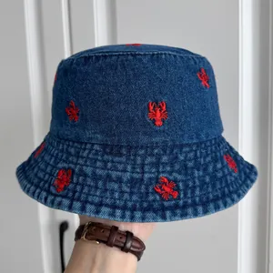 Detailed macro view of a blue denim bucket hat with vibrant red strawberry embroidery