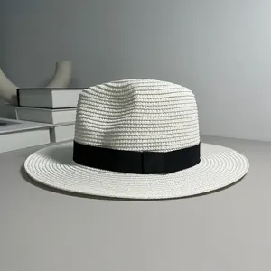 High quality detail view of a woven white Panama straw hat with an elegant black ribbon band