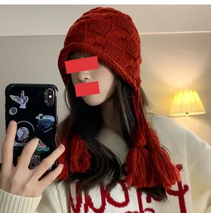 Detailansicht der roten Strickmütze mit handgemachter Textur und langen Quasten