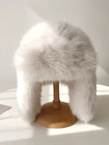 Primer plano de un gorro Ushanka de piel sintética blanca en un soporte de madera