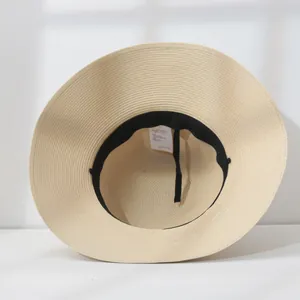 Inside view of a straw sun hat showing the black sweatband and white care label.