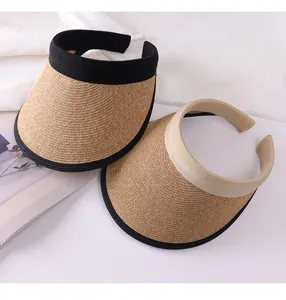 Detail view of two women's woven straw sun visors with wide brims and black trim finish.