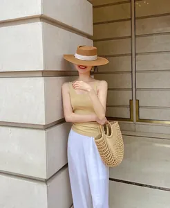 Stylish women's summer flat top straw hat with a white band for beach sun protection